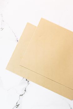 Beige A4 papers on white marble background as office stationery flatlay, luxury branding flat lay and brand identity design for mockups