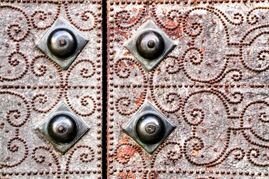 Old gray metal door of a church with wrought iron details in Murcia, Spain