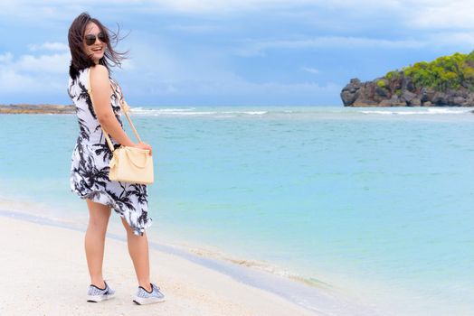 Landscape of the beach and the sea in summer sky and cheerful woman tourist wearing sunglasse, looking at the camera and laughing on Tarutao island, Satun, Thailand