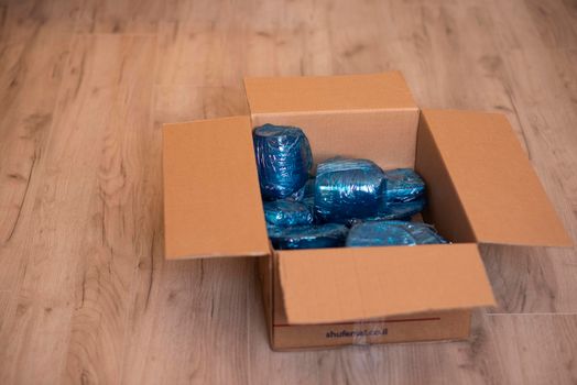 Glassware wrapped with blue wrapping nylon at the bottom of a cardboard box. High quality photo