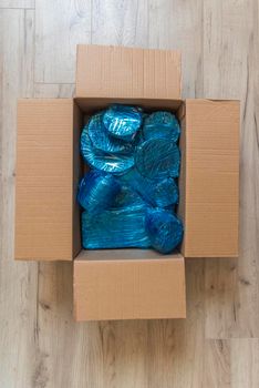 Glassware wrapped with blue wrapping nylon at the bottom of a cardboard box. High quality photo