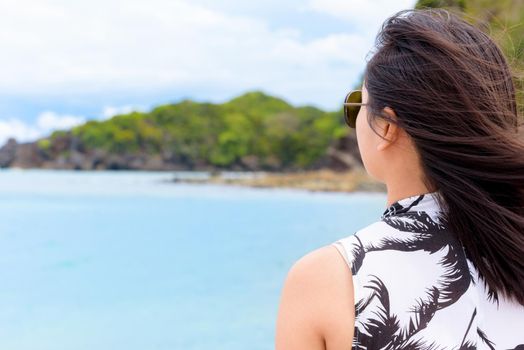 Woman tourist wearing sunglasse looking at beautiful nature landscape of the beach and sea in summer sky background at Koh Tarutao island National Park, Satun, Thailand