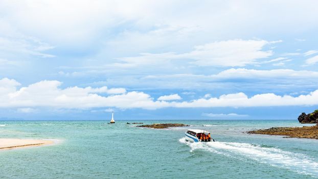 Speed boat passenger with tourists on the sea is leaving the coast of Tarutao island, beautiful nature in summer at Tarutao National Park is a famous attractions of Satun, Thailand, 16:9 widescreen
