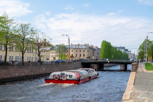 St. Petersburg, Russia - May 16, 2021. View of the Kryukov Canal and a pleasure motor ship sailing along it on a warm spring day. Selective focus.