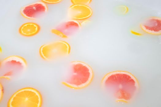 Oranges, lemons and grapefruits in milk bath - white water. Spa and skin care concept. Horizontal photo