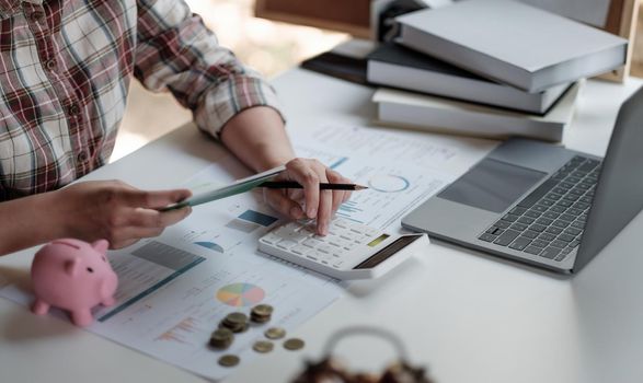 Woman calculating her Debt. woman hand calculating her monthly expenses during tax season with coins, calculator and account bank