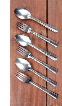 forks and spoons on wooden plank background