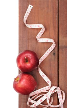 closeup fresh ripe red apples and tape measure on wooden plank