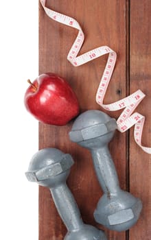 closeup fresh ripe red apples dumbbells and tape measure on wooden plank