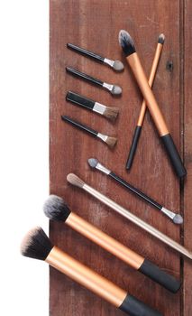 closeup makeup brush cosmetics on wooden plank background