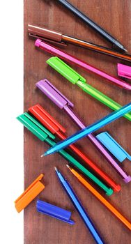 many colorful pens on wooden plank, working background