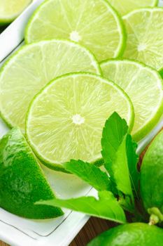 closeup sliced fresh green limes in white plate