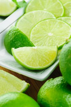 closeup sliced fresh green limes in white plate