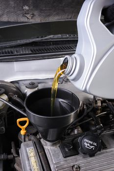 technician pouring fresh motor oil to engine of old car