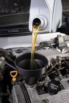 technician pouring fresh motor oil to engine of old car
