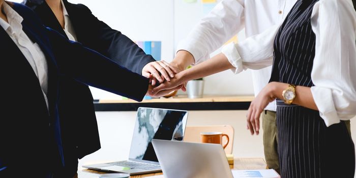 As they laugh and celebrate their performance, the business team makes a handshake motion