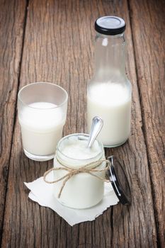 fresh natural yogurt in glass on wooden plank