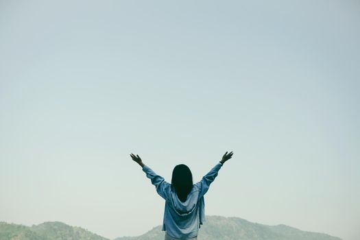 Woman rise hands up to sky freedom concept with blue sky and summer field mountain background.