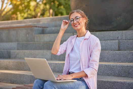 Businesswoman sitting stairs summer park using laptop Business persone working remote. Outdoor Successful european caucasian woman freelancer make video call teacher study work online lessons