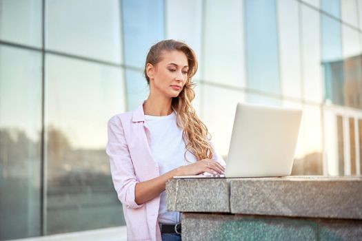 Businesswoman standing corporate building summer day using laptop Business person working remote Successful european caucasian woman freelancer make video call teacher study work online lessons