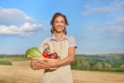Woman farmer holding basket vegetable onion tomato salad cucumber standing farmland smiling Female agronomist specialist farming agribusiness Happy Girl dressed apron cultivated wheat field
