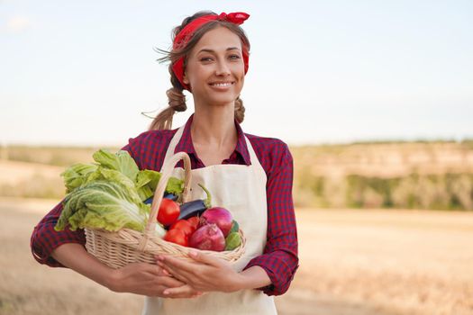 Woman farmer holding basket vegetable onion tomato salad cucumber standing farmland smiling Female agronomist specialist farming agribusiness Pretty girl dressed red checkered shirt and bandana