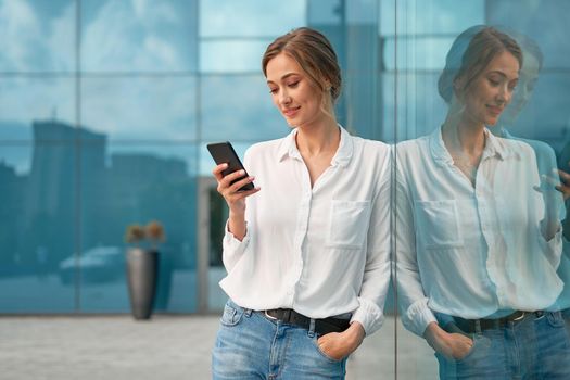 Businesswoman successful woman business person standing outdoor corporate building exterior cell phone Pensive elegance cute caucasian professional business woman middle age dreaming with mobile phone