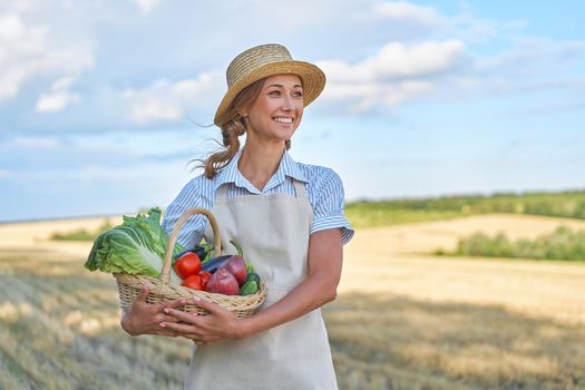 Woman farmer straw hat holding basket vegetable onion tomato salad cucumber standing farmland smiling Female agronomist specialist farming agribusiness Happy Girl dressed apron cultivated wheat field