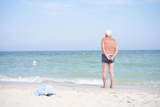 Alone unrecognizable senior man standing sea beach watching horizon rear view Sadness loneliness ageing solitude aged