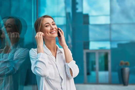 Businesswoman successful woman business person standing outdoor corporate building exterior cell phone Pensive elegance cute caucasian professional business woman middle age dreaming with mobile phone