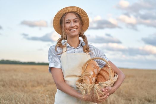 Female farmer standing wheat agricultural field Woman baker holding wicker basket bread eco product Baking small business Caucasian person dressed straw hat apron organic healthy food concept