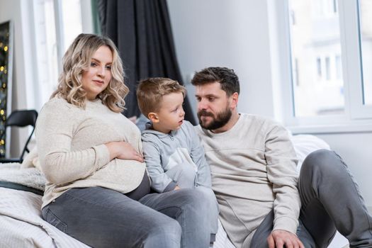 Happy family concept Mother father and little son have fun at home Caucasian family indoors Pregnant mom beard dad and funny little boy