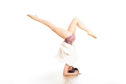 Portrait of active sporty young woman performing standing on head yoga pose in yoga studio. Healthy active lifestyle.