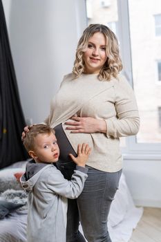 Cute child hugging belly pregnant mother New life and pregnancy concept Little boy embrace big belly mom Waiting for brother Caucasian family indoor