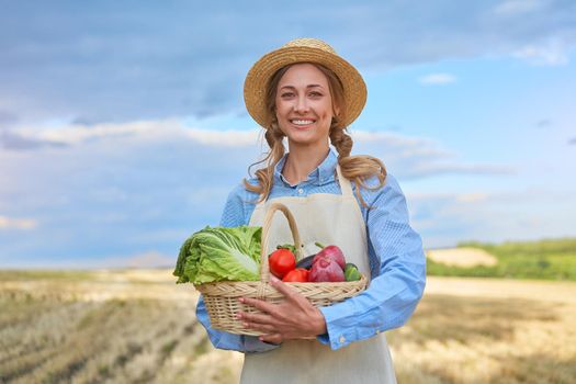 Woman farmer straw hat holding basket vegetable onion tomato salad cucumber standing farmland smiling Female agronomist specialist farming agribusiness Happy Girl dressed apron cultivated wheat field