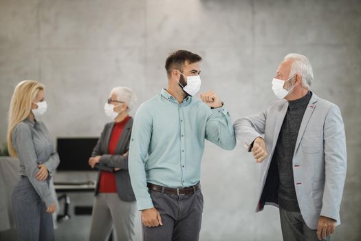 A two businessman greeting with bumping elbows in a modern office during corona virus pandemic to avoid handshakes.