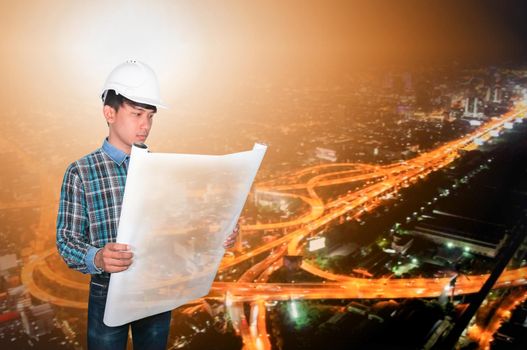 Engineer open hold blueprints in construction concept with night cityscape Blurred background
