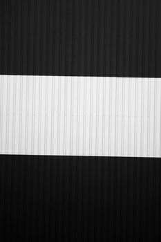 Black and white corrugated iron sheet used as a facade of a warehouse or factory. Texture of a seamless corrugated zinc sheet metal aluminum facade. Architecture. Metal texture