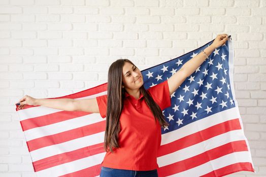 Independence day of the USA. Happy July 4th. Young smiling woman with national flag of the USA.