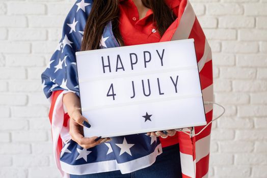 Independence day of the USA. Happy July 4th. Woman with american flag holding lightbox with words Happy 4 July