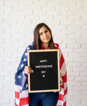 Independence day of the USA. Happy July 4th. Woman with american flag holding letter board with words Happy Independence Day