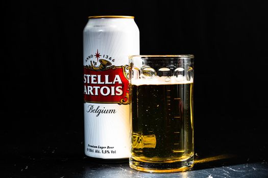 Can of Stella Artois beer and beer glass on dark background. Illustrative editorial photo shot in Bucharest, Romania, 2021