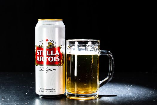 Can of Stella Artois beer and beer glass on dark background. Illustrative editorial photo shot in Bucharest, Romania, 2021