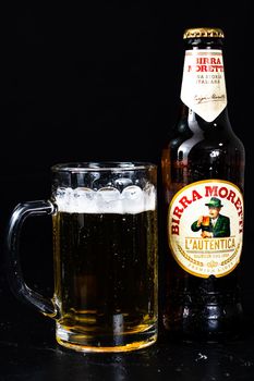 Can of Birra Morreti beer and beer glass on dark background. Illustrative editorial photo shot in Bucharest, Romania, 2021