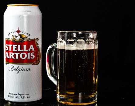 Can of Stella Artois beer and beer glass on dark background. Illustrative editorial photo shot in Bucharest, Romania, 2021