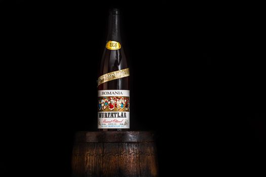 Vintage Murfatlar wine bottle on wooden barrel with dark background. Illustrative editorial photo Bucharest, Romania, 2021