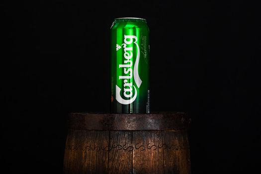 Can of Carsberg beer on beer barrel with dark background. Illustrative editorial photo shot in Bucharest, Romania, 2021