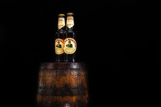 Bottle of Birra Moretti beer on wooden barrel with dark background. Illustrative editorial photo Bucharest, Romania, 2021