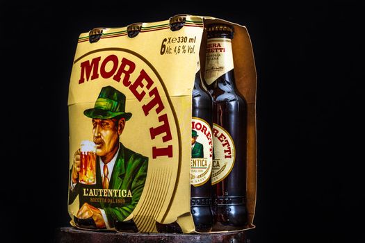 6 pack of Birra Moretti beer on wooden barrel with dark background. Illustrative editorial photo Bucharest, Romania, 2021