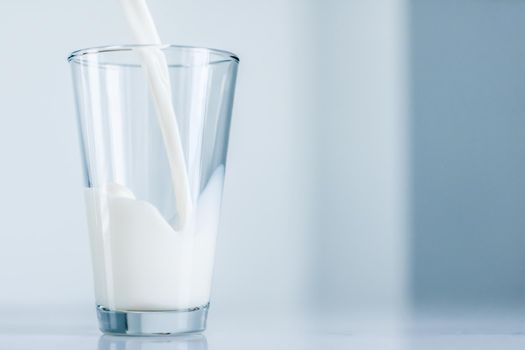 Dairy, healthy nutrition and breakfast concept - World Milk Day, pouring into glass on marble table